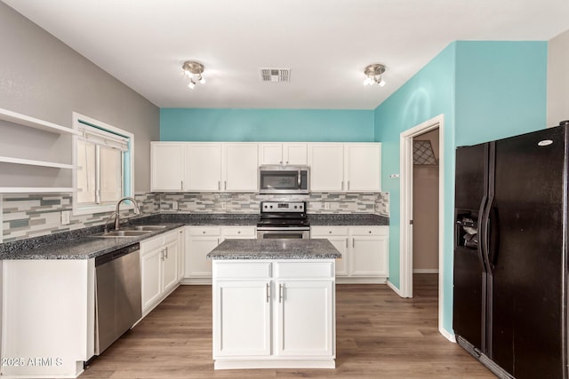 kitchen with sink, white cabinets, decorative backsplash, a center island, and stainless steel appliances