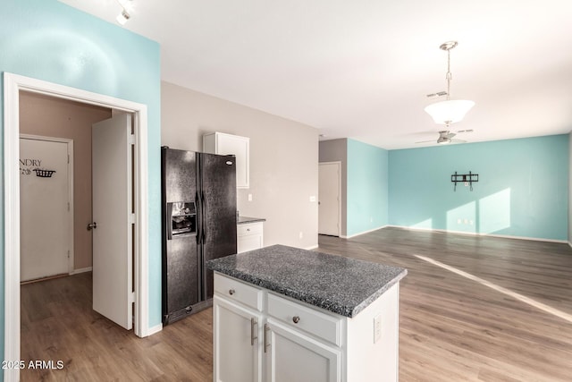 kitchen featuring black fridge, a center island, hanging light fixtures, light hardwood / wood-style floors, and white cabinets