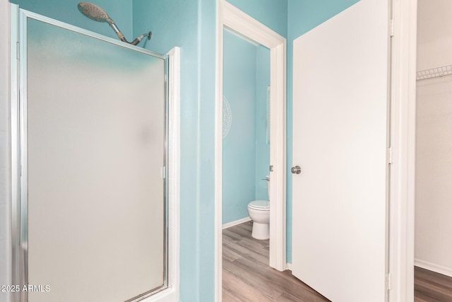 bathroom with wood-type flooring, toilet, and a shower with shower door