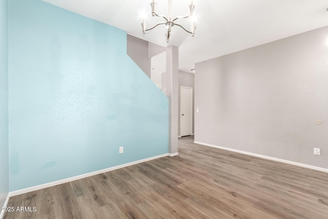 empty room featuring a chandelier and hardwood / wood-style floors