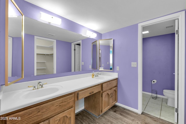 bathroom with visible vents, a sink, toilet, and double vanity