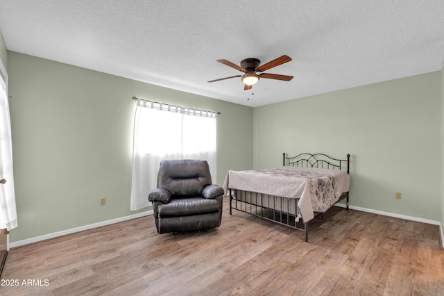 bedroom featuring ceiling fan, light hardwood / wood-style flooring, and a textured ceiling