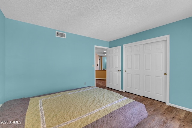 bedroom with hardwood / wood-style floors, a textured ceiling, and a closet