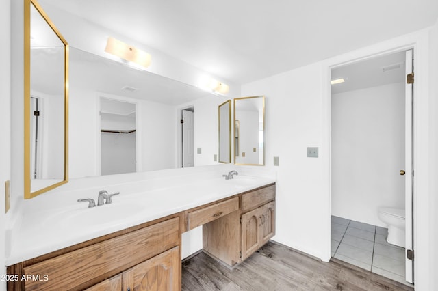 full bath featuring double vanity, toilet, a sink, and wood finished floors