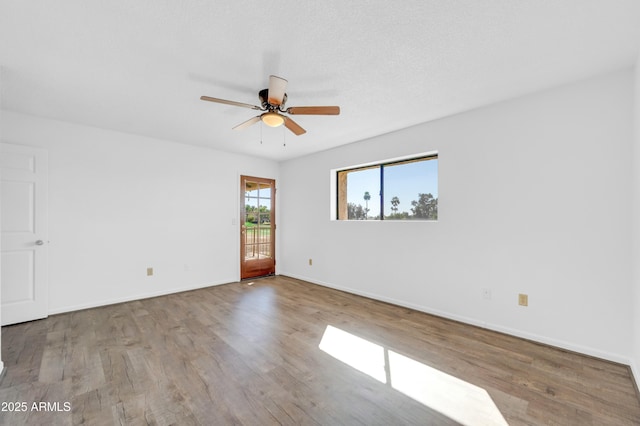 spare room featuring ceiling fan, a textured ceiling, baseboards, and wood finished floors