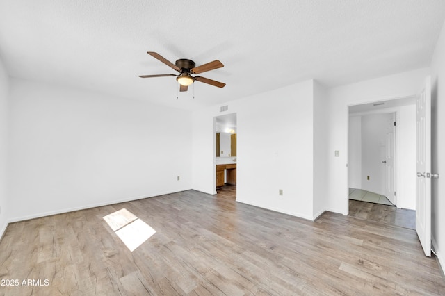 unfurnished bedroom featuring visible vents, ceiling fan, ensuite bath, and wood finished floors