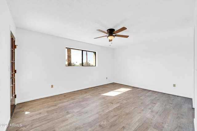 empty room featuring baseboards, a ceiling fan, and wood finished floors