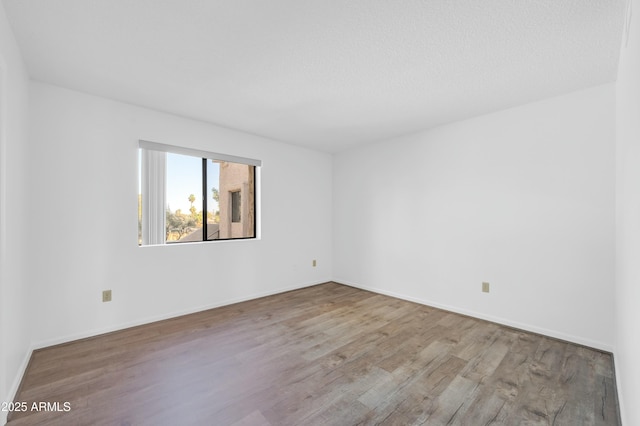 spare room with baseboards and wood finished floors