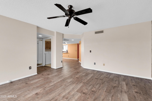 unfurnished living room with visible vents, a textured ceiling, baseboards, and wood finished floors