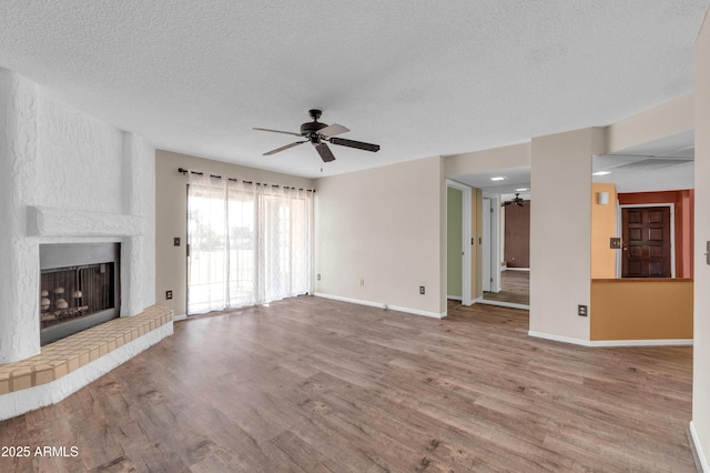 unfurnished living room with a large fireplace, hardwood / wood-style floors, a textured ceiling, and ceiling fan