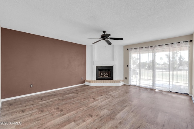 unfurnished living room with ceiling fan, wood-type flooring, a fireplace, and a textured ceiling