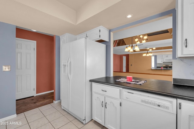 kitchen with white appliances, an inviting chandelier, hanging light fixtures, white cabinets, and light tile patterned flooring