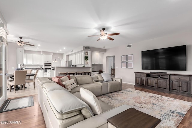 living room featuring recessed lighting, visible vents, ceiling fan, and light wood-style flooring