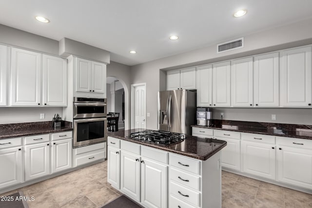 kitchen with arched walkways, visible vents, white cabinets, and appliances with stainless steel finishes