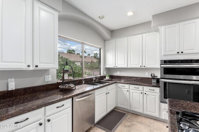 kitchen featuring dark stone countertops, recessed lighting, appliances with stainless steel finishes, white cabinets, and a sink