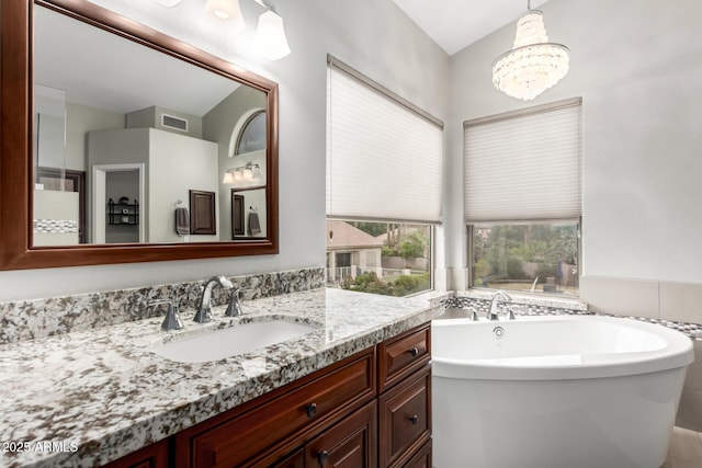 bathroom featuring a chandelier, visible vents, vanity, and a soaking tub