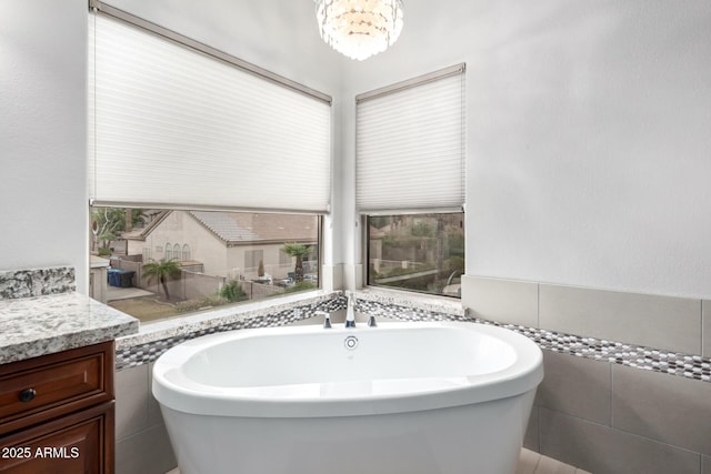 bathroom with vanity, tile walls, a freestanding tub, and a chandelier