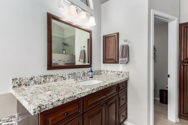 bathroom featuring a shower, baseboards, and vanity