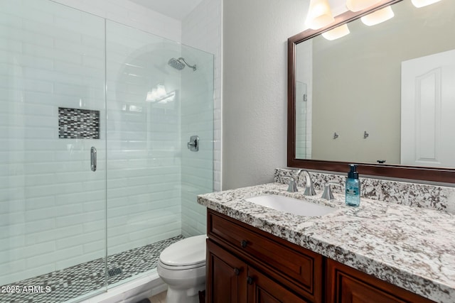 full bath featuring vanity, toilet, a textured wall, and a stall shower