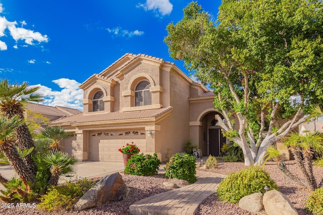 mediterranean / spanish home featuring stucco siding, an attached garage, a tile roof, and driveway