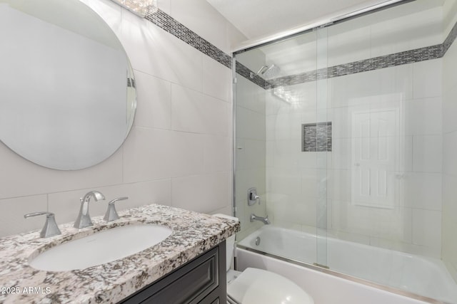 full bath featuring vanity, tile walls, toilet, and enclosed tub / shower combo