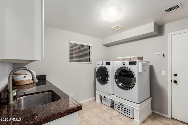 washroom with cabinet space, visible vents, independent washer and dryer, and a sink