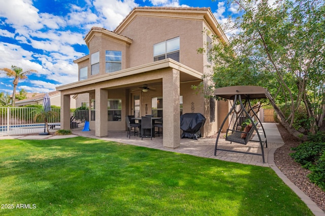 back of property with stucco siding, a yard, a fenced backyard, a patio area, and a ceiling fan