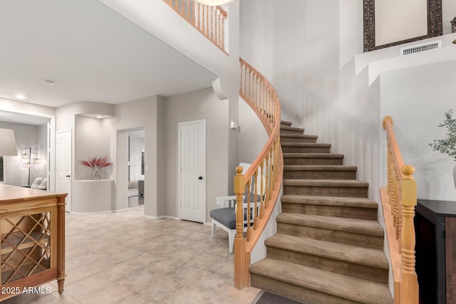 staircase with baseboards and a towering ceiling