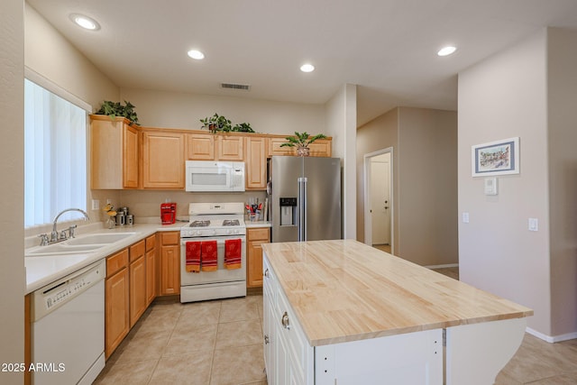 kitchen with light tile patterned flooring, sink, butcher block countertops, a center island, and white appliances