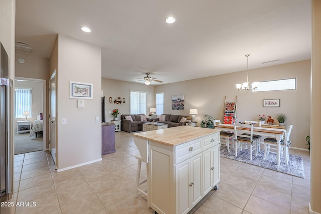 kitchen with light tile patterned floors, a breakfast bar, a center island, white cabinets, and decorative light fixtures