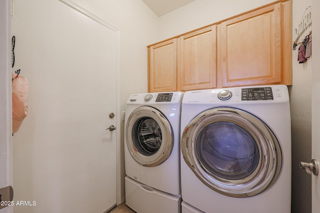 clothes washing area featuring cabinets and washing machine and clothes dryer