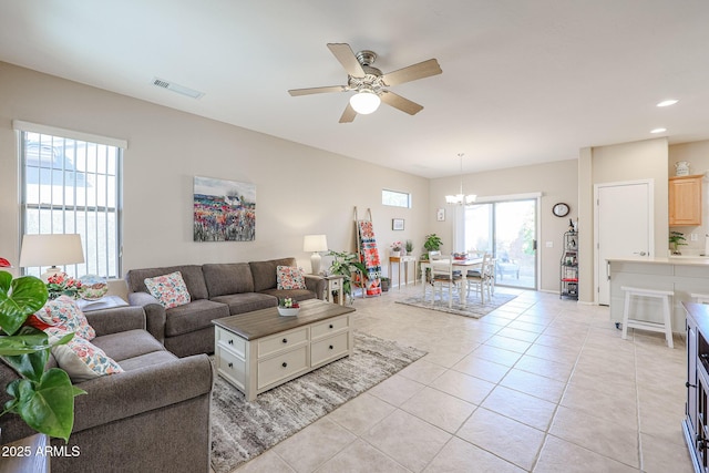 living room with light tile patterned flooring and ceiling fan with notable chandelier