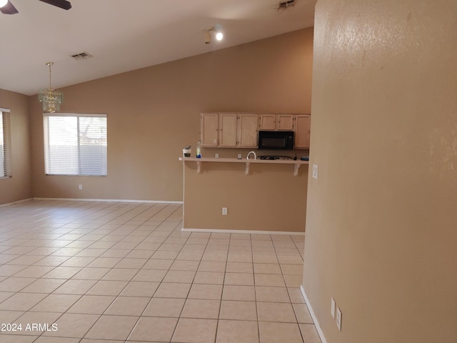 interior space featuring light tile patterned floors, decorative light fixtures, high vaulted ceiling, and a breakfast bar area