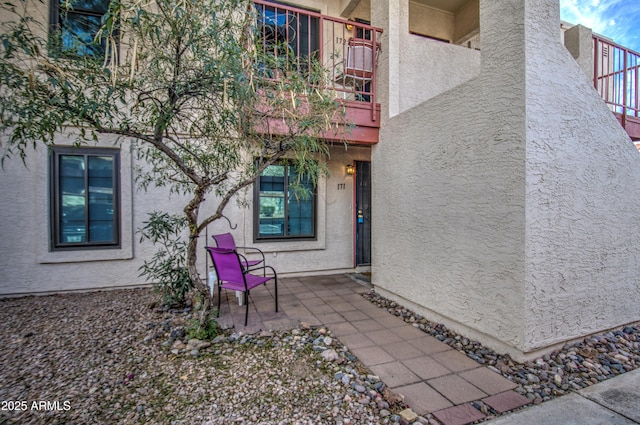 view of exterior entry with a patio area and a balcony