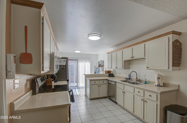 kitchen featuring sink, a textured ceiling, light tile patterned floors, appliances with stainless steel finishes, and kitchen peninsula