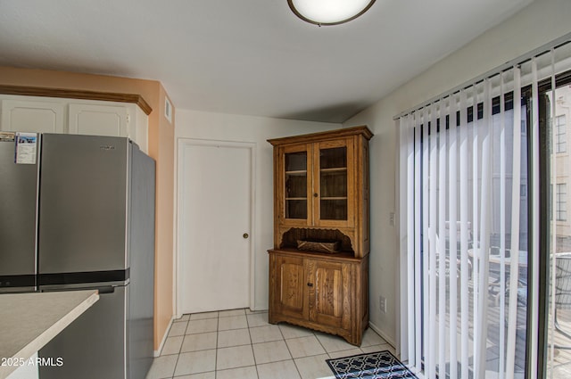 kitchen with stainless steel fridge, white cabinets, and light tile patterned flooring