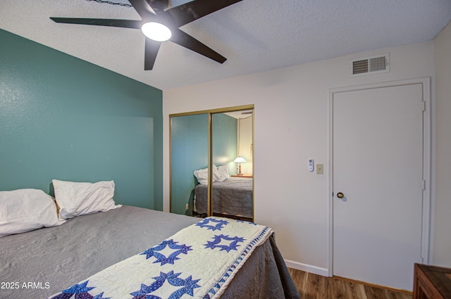 bedroom featuring wood-type flooring, ceiling fan, a textured ceiling, and a closet