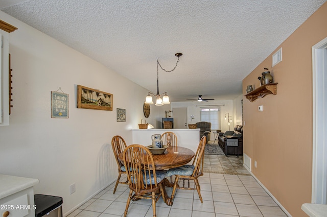 tiled dining space featuring ceiling fan with notable chandelier and a textured ceiling