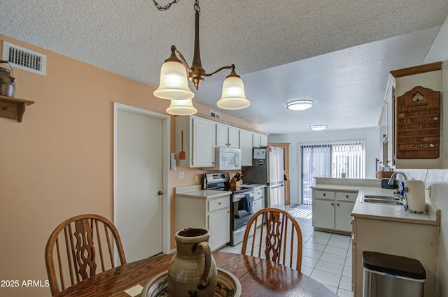 dining space featuring light tile patterned floors, sink, and a textured ceiling