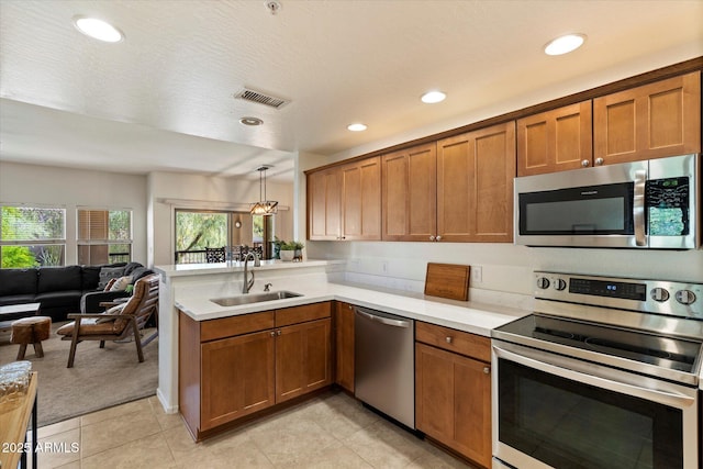 19700 N 76th St Unit 2086, Scottsdale, AZ 85255 - kitchen with visible vents, a peninsula, brown cabinets, appliances with stainless steel finishes, and a sink