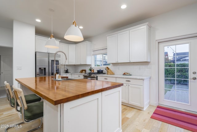 kitchen with stainless steel appliances, a center island, hanging light fixtures, and white cabinets