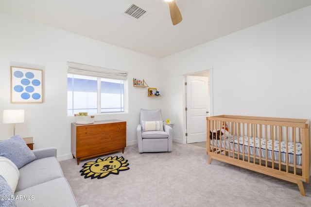 bedroom with ceiling fan, light carpet, and a crib