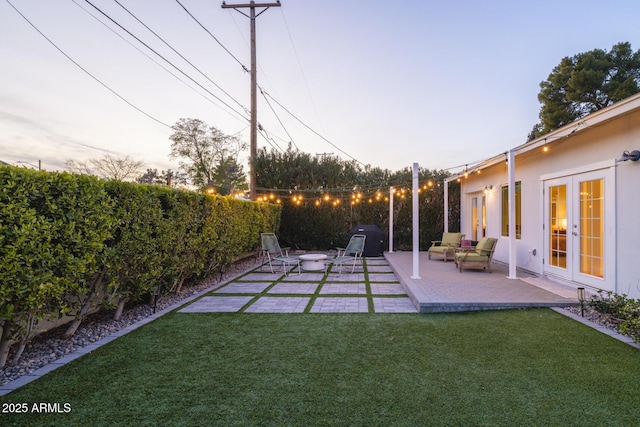 yard at dusk with a patio and french doors