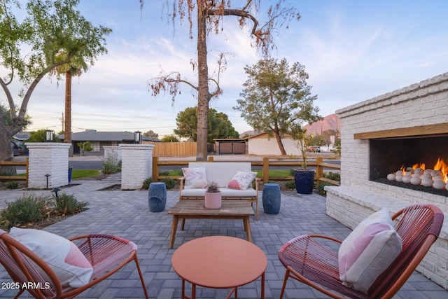 patio terrace at dusk with an outdoor living space with a fireplace