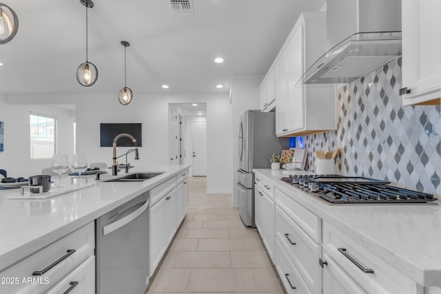 kitchen featuring light stone countertops, wall chimney exhaust hood, stainless steel appliances, sink, and white cabinetry