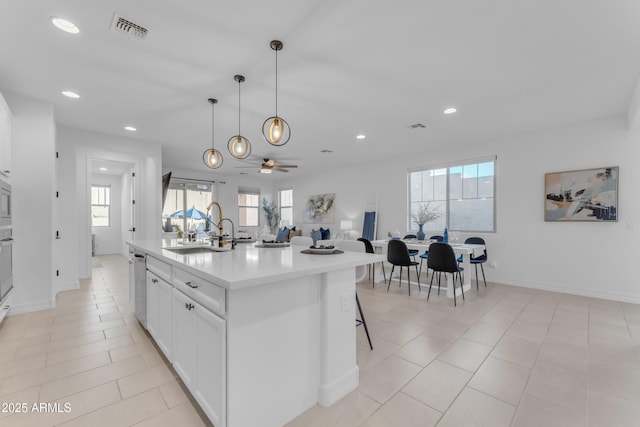 kitchen featuring sink, stainless steel dishwasher, ceiling fan, an island with sink, and white cabinetry