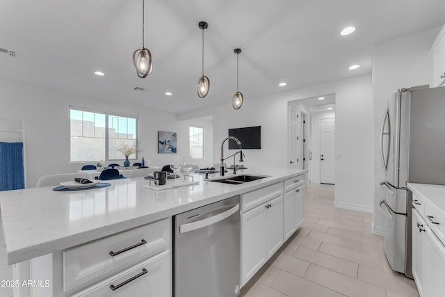 kitchen featuring white cabinets, stainless steel appliances, a kitchen island with sink, and sink