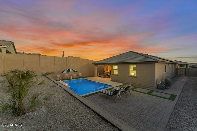 pool at dusk with a patio area