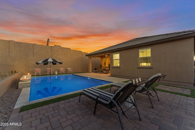 pool at dusk with a patio area