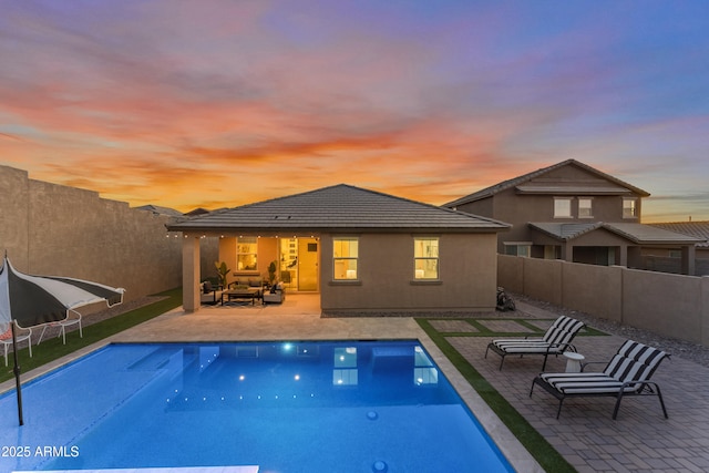 pool at dusk with a patio area and an outdoor living space